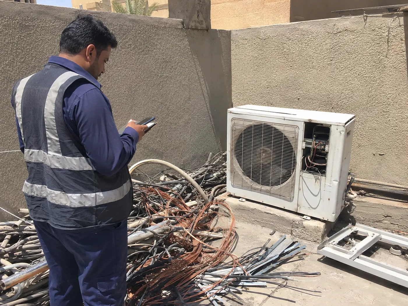 Inspector reviewing copper cables and an air conditioner at a customer site